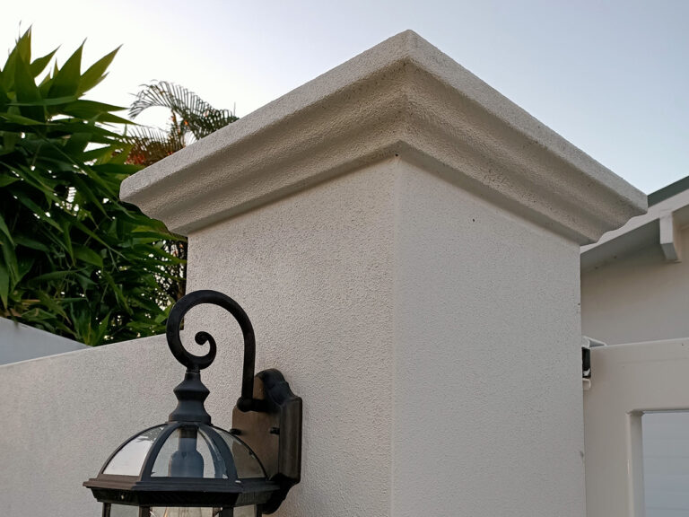 Square pier caps and matching fence capping on a rendered boundary wall Square pier caps and matching fence capping on a rendered boundary wall